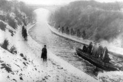 An ice-breaking barge being towed by at least ten draft horses.